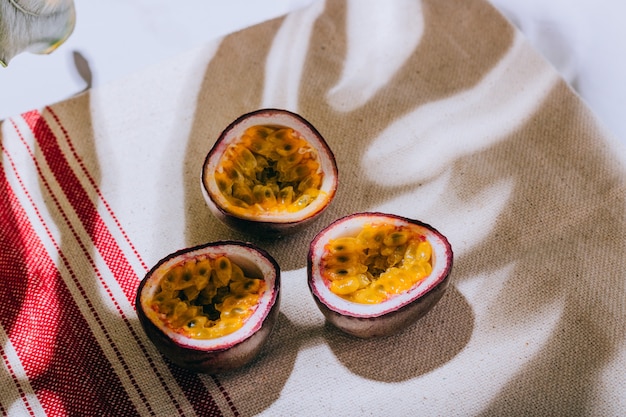 Sliced passion fruit on linen napkin, tropical concept with hard light and monstera shadow.