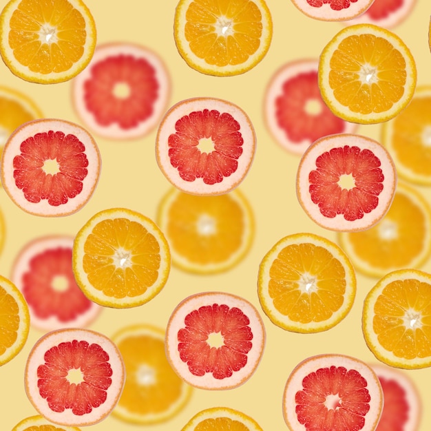 Sliced pieces of orange lime and grapefruit on a green background Seamless pattern