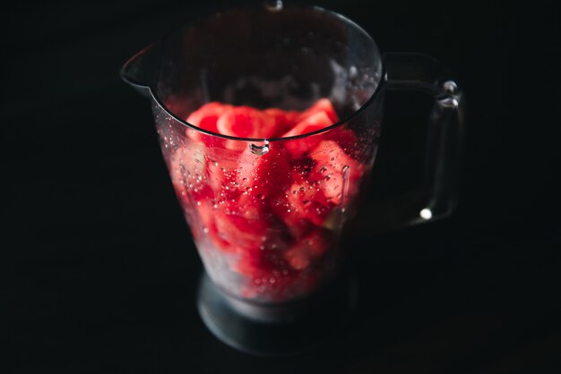 Sliced pieces of watermelon in the shape of hearts in a glass dish on a dark wall