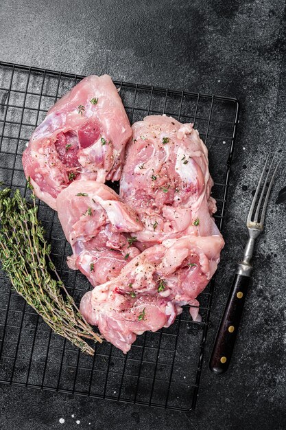 Sliced raw Chicken leg thigh fillet meat ready for cooking with spices Black background Top view