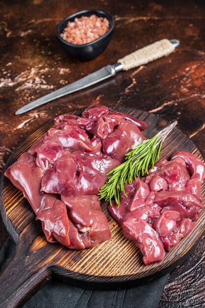 Sliced Raw chicken liver fresh fowl offals on wooden board Dark background Top view