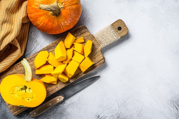 Sliced raw orange pumpkin on a chopping Board. White background