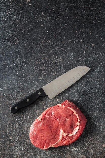 Sliced raw ribeye steak on a black kitchen table Top view