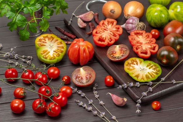 Sliced red and green tomatoes on cutting board Branch of cherry tomato and parsley in jar