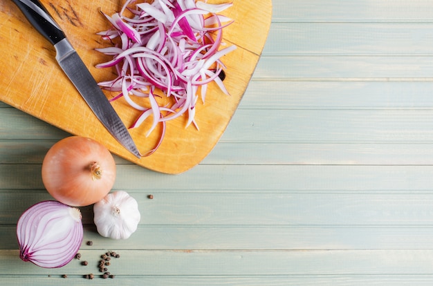 sliced red onion and kitchen knife on wooden board