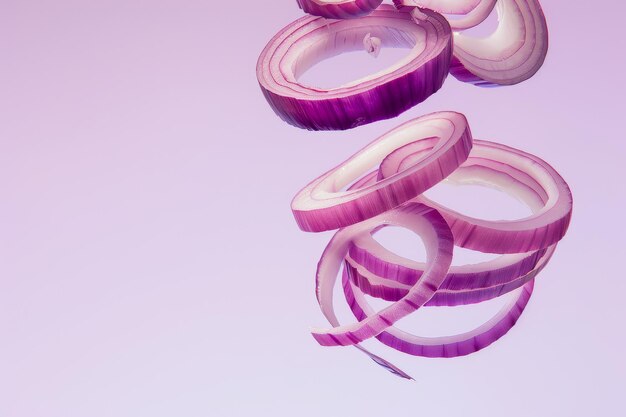 Photo sliced red onion rings floating against pastel pink background in minimalist abstract art