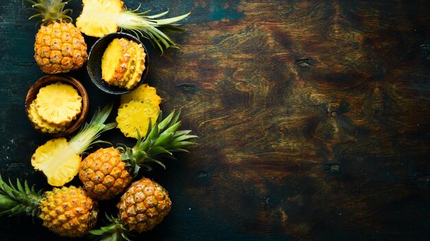 Sliced ripe baby pineapple on a black stone background Tropical fruits Top view Free space for text