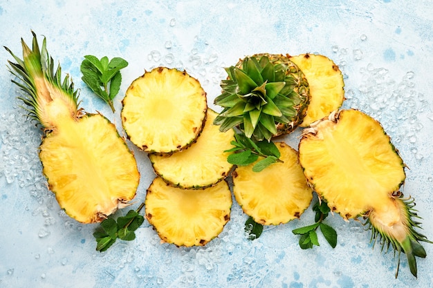 Sliced ripe pineapple on light blue stone background. Tropical fruits. Top view. Free space for text. 