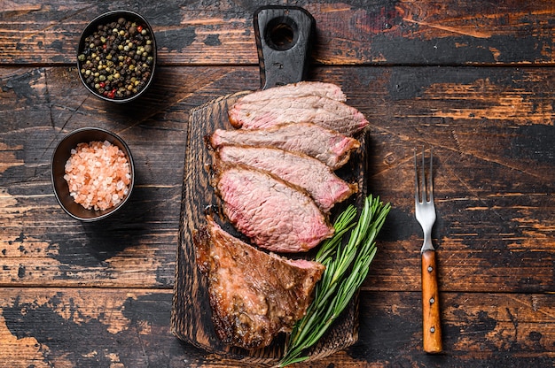 Sliced Roast beef sirloin tri tip steak bbq. Dark  wooden table. Top view.