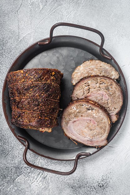 Photo sliced roast pork meat  roulade on a steel tray white background top view