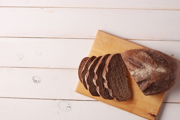 Sliced rye bread on cutting board on white wooden table