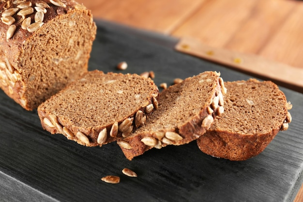 Sliced rye bread with seeds on wooden cutting board closeup