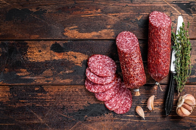 Sliced salami cured sausage on kitchen table. Wooden background. Top view. Copy space.