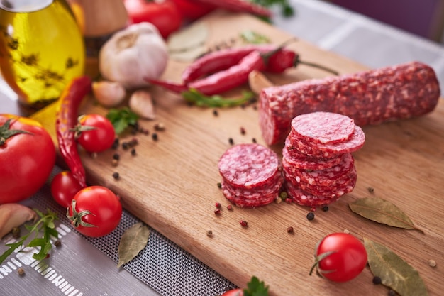 Sliced salami sausage on wooden cutting board at domestic kitchen