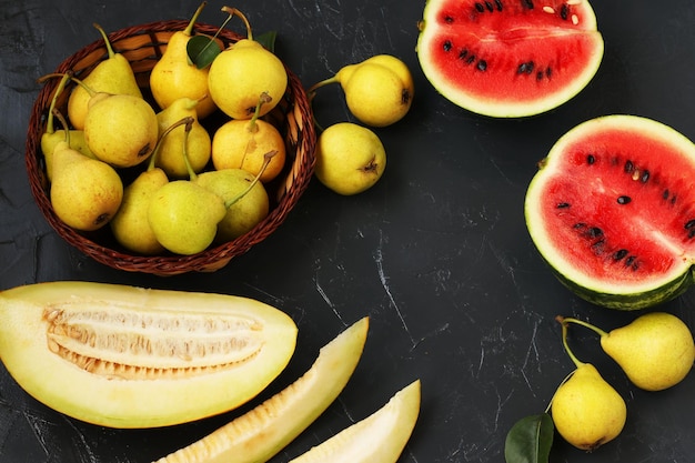 Sliced slices of watermelon and melon ripe yellow pears against a dark background horizontal format