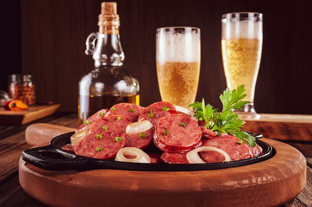 Sliced smoked fried calabrese sausage with onion and beer - Brazilian appetizer