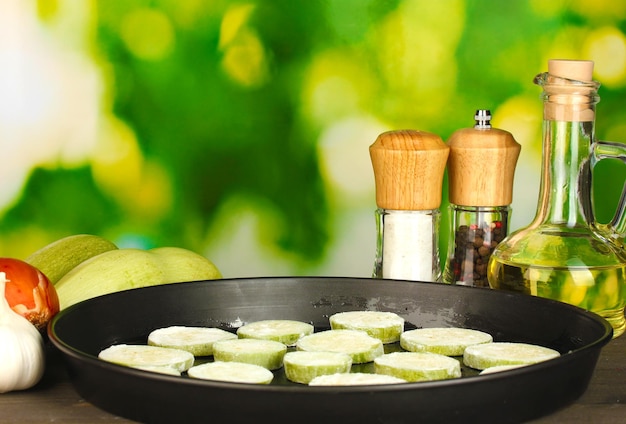 Sliced squash in a pan on wooden table on green background closeup