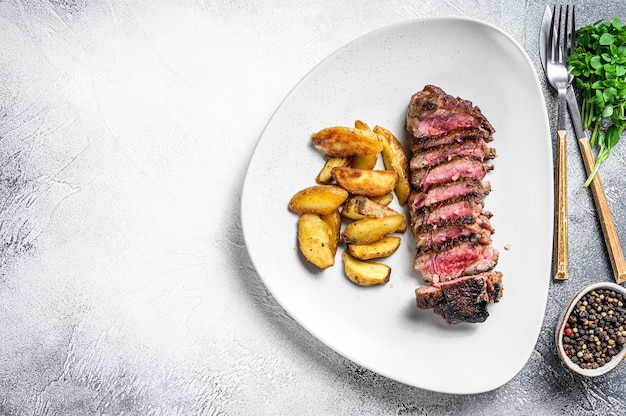 Sliced striploin steak with potato.   Top view.  