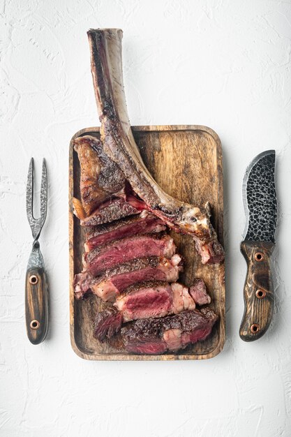 Sliced Tomahawk Steak on the bone on wooden serving board