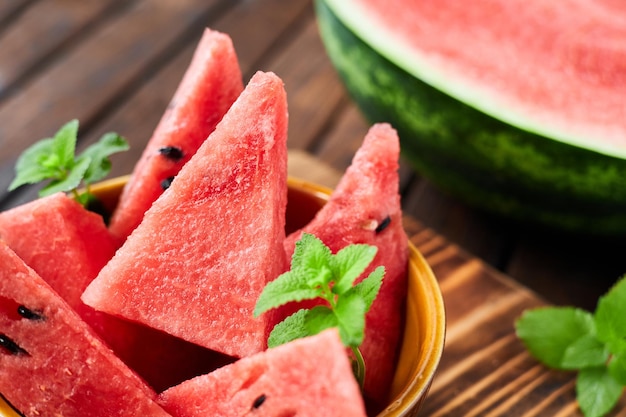 Sliced watermelon decorated with mint leaves on brown wooden background