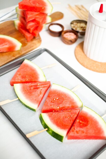 Sliced watermelon in triangle shapes on wooden sticks.