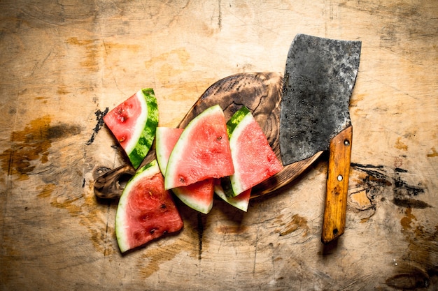 Sliced watermelon with an axe. On wooden background.