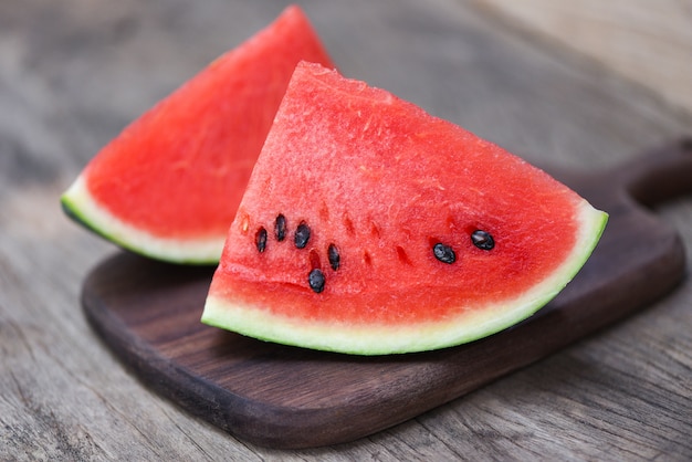 Sliced watermelon on wooden cutting board. Close up fresh watermelon pieces tropical summer fruit