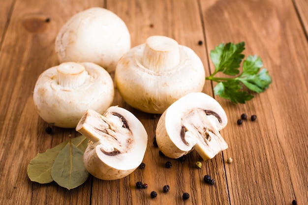 Sliced and whole champignons, Bay leaf, parsley and black pepper on a wooden table