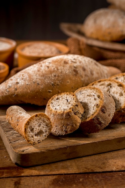 Sliced whole grain bread,
baguettes on rustic wood with whole flour pot in the background.