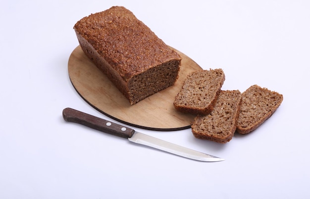 Sliced whole grain rye bread with knife on white background