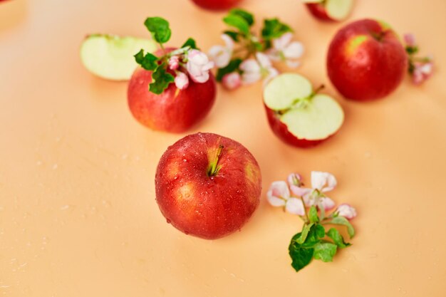 Sliced whole red apple and flowers a flat lay on a pastel orange background