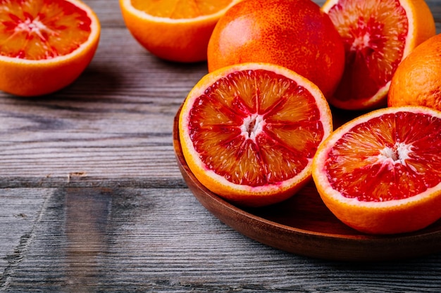 Sliced and whole ripe juicy Sicilian Blood oranges on wooden background Selective focus