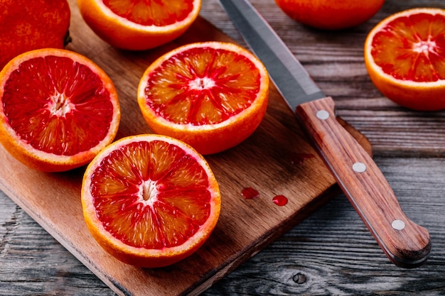 Sliced and whole ripe juicy Sicilian Blood oranges on wooden background Selective focus