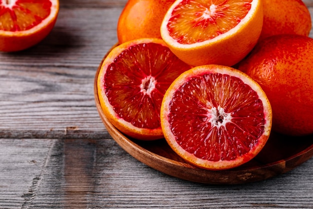 Sliced and whole ripe juicy Sicilian Blood oranges on wooden background Selective focus