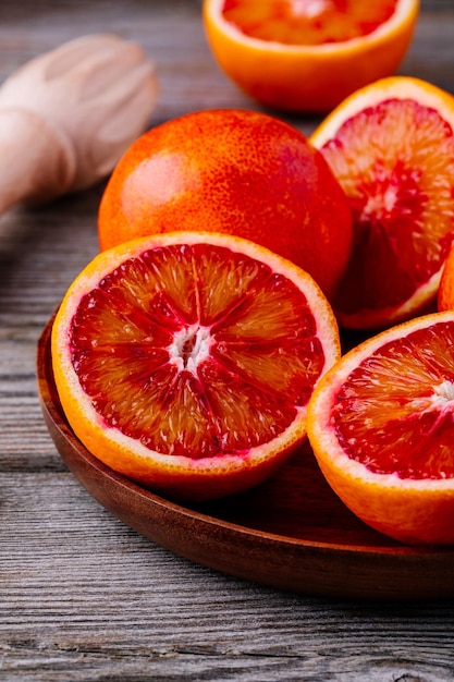 Sliced and whole ripe juicy Sicilian Blood oranges on wooden background Selective focus