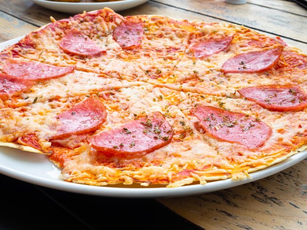 Sliced whole salami pizza on a wooden table