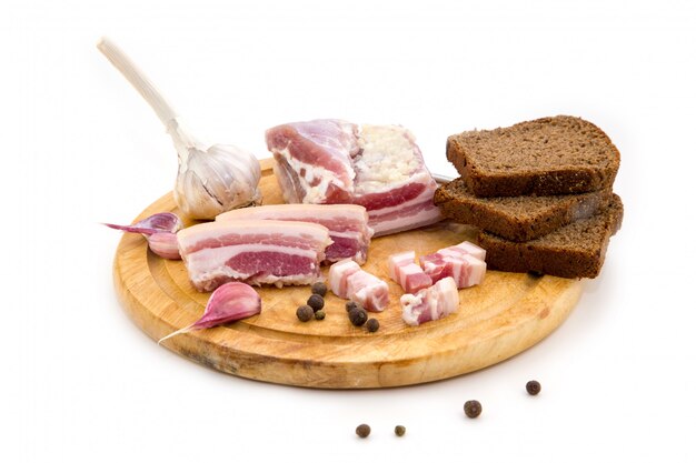 Slices of bacon and sliced fat with bread and garlic on a wooden board.