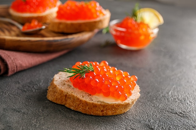 Slices of bread with red caviar on dark background.