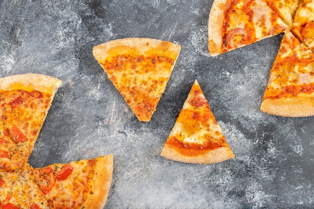 Slices of delicious cheesy pizza placed on stone background. 