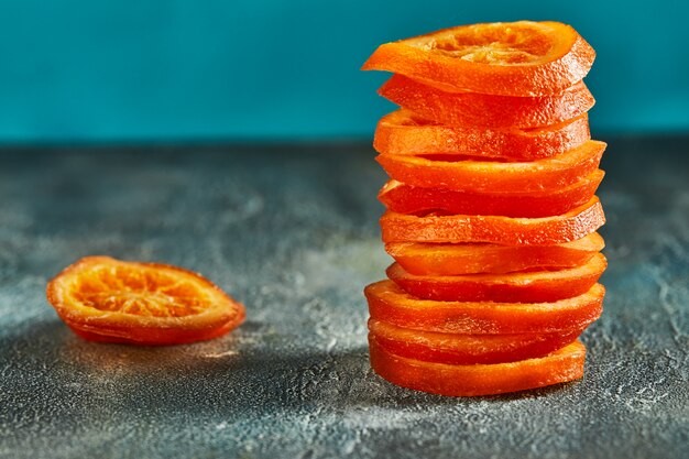 Slices of dried oranges or tangerines on a blue wall. Vegetarianism and healthy eating. Copy space