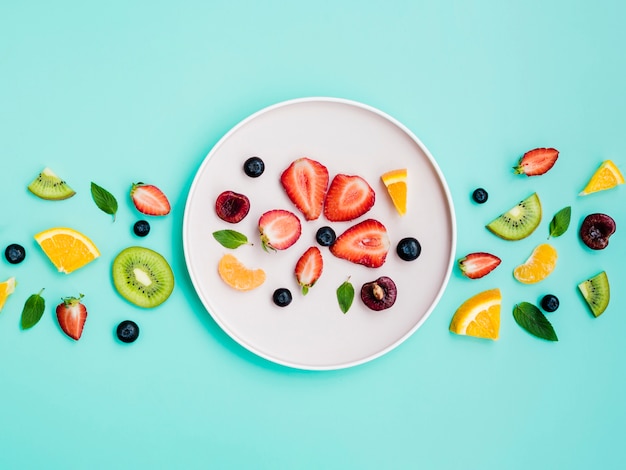 Slices of exotic sweet fruit on white plate on turquoise background