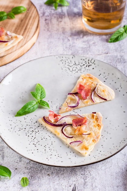 Slices French tarte flammkuchen with bacon cream cheese and onion on a plate Vertical view