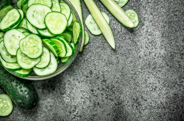 Slices of fresh cucumbers in a bowl. On a rustic background.