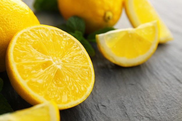 Slices of fresh lemon with green leaves on table closeup