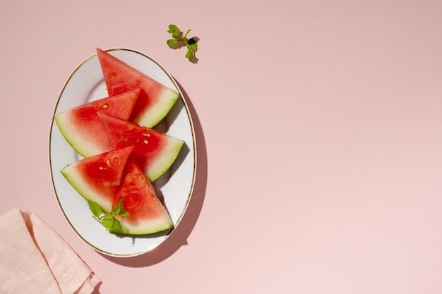 Slices of fresh watermelon in a plate top view pink background Summer foods Copy space