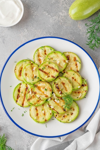 Slices of fried zucchini with garlic and fresh dill on a plate Vegetarian healthy dish