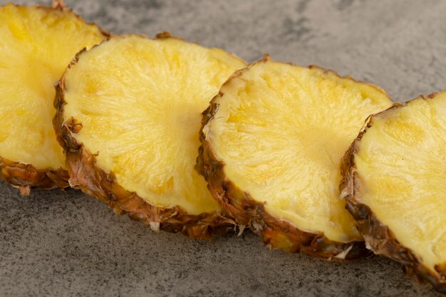 Slices of juicy delicious pineapple placed on stone surface.