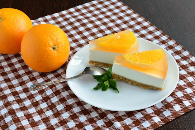 slices of orange cheesecake with teaspoon on the brown tablecloth