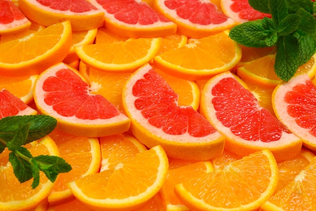 Slices of oranges and a grapefruits and mint as a background