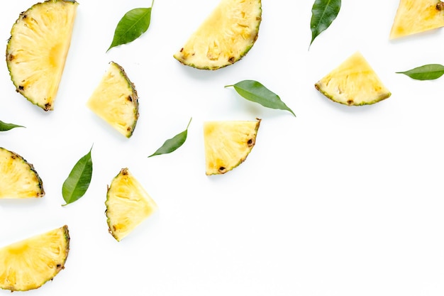 Slices pineapple with green leaves isolated on white background flat lay top view